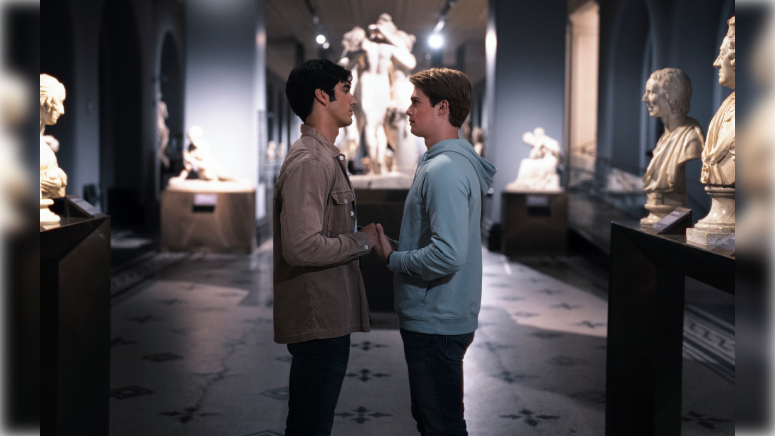 Alex (a Mexican-American male with black hair) and Prince Henry (a Caucasian male with auburn hair) holds hands in the Dorothy & Micheal Hintze Sculpture Galleries of the Victoria & Albert Museum.